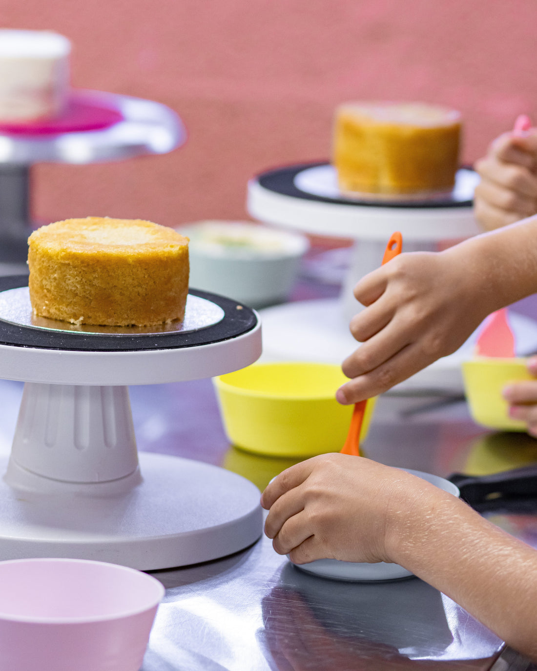 hands mixing buttercream with cake in background