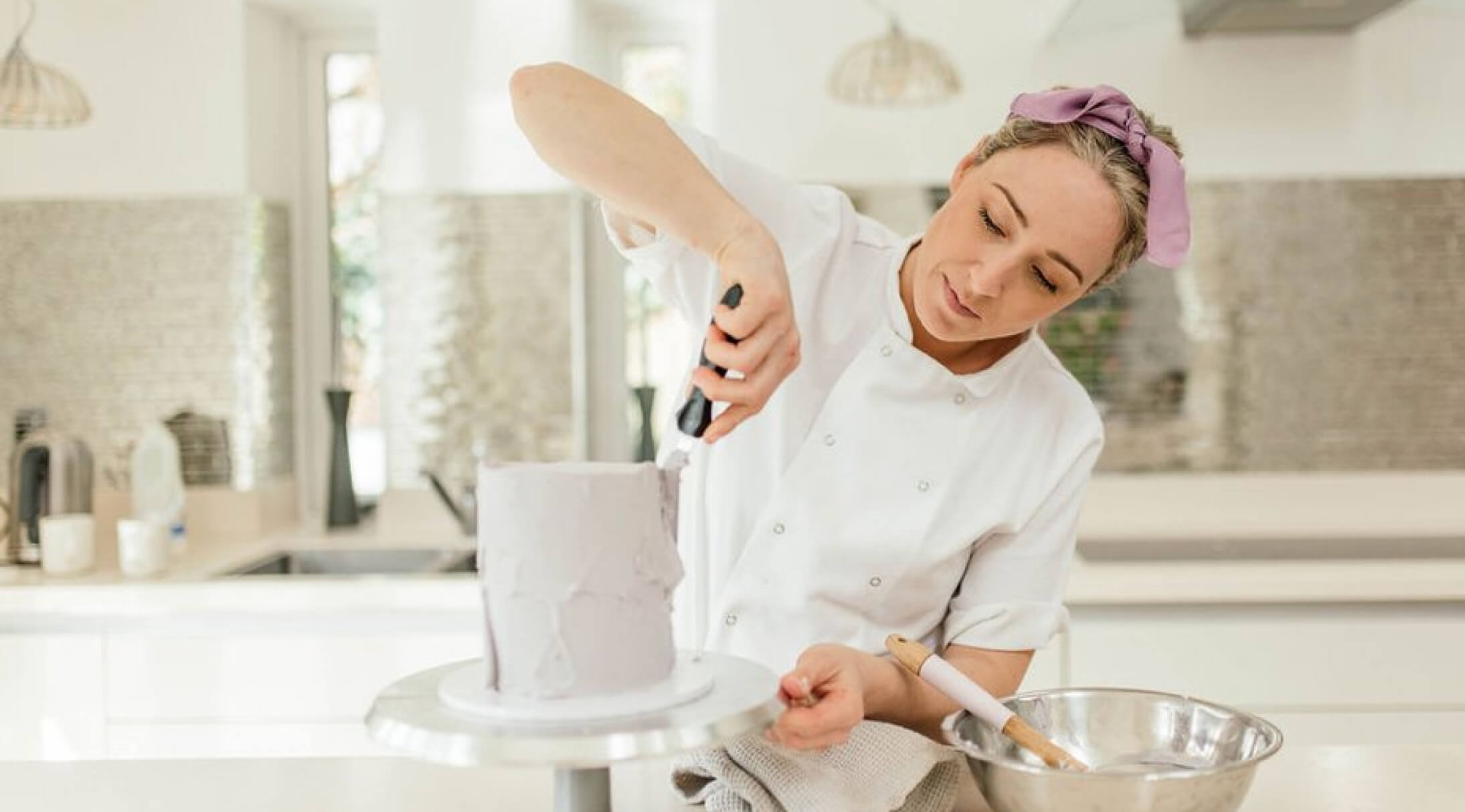 Founder smoothing the icing on a custom celebration cake