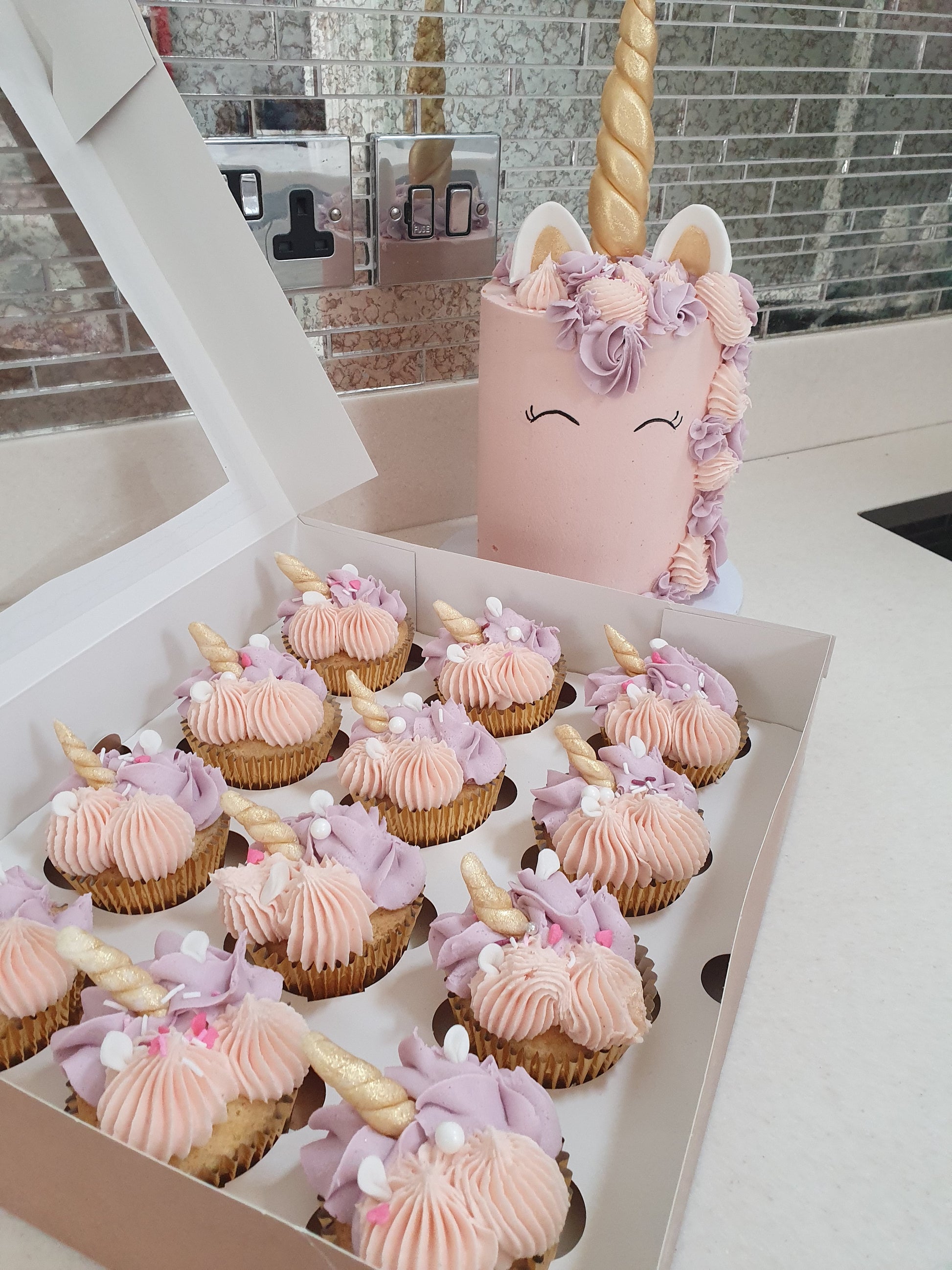 Unicorn celebration cake displayed alongside matching unicorn cupcakes